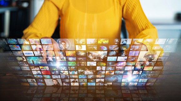A woman looking at a bunch of miniature video screen windows.