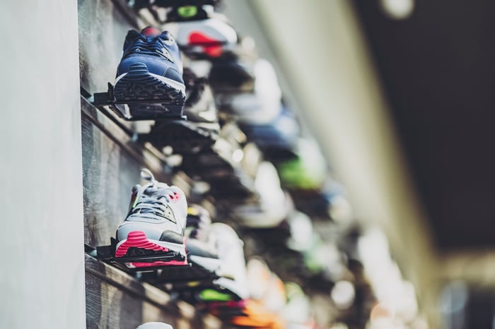 Rows of sneakers line shelves in a sporting goods store.