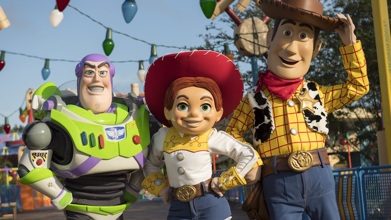 Costumed Woody, Jessie, and Buzz Lightyear characters at Disney World's Toy Story Land.