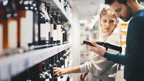 Photograph of young couple in liquor store looking at a bottle of wine.