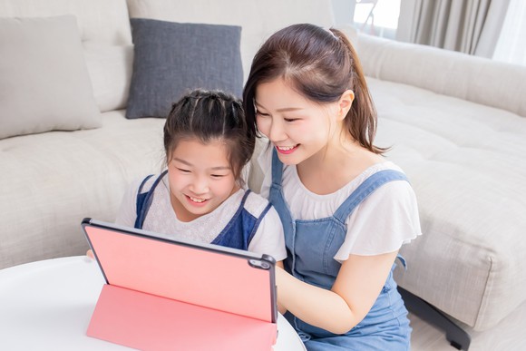 A woman and a young girl looking at a tablet.