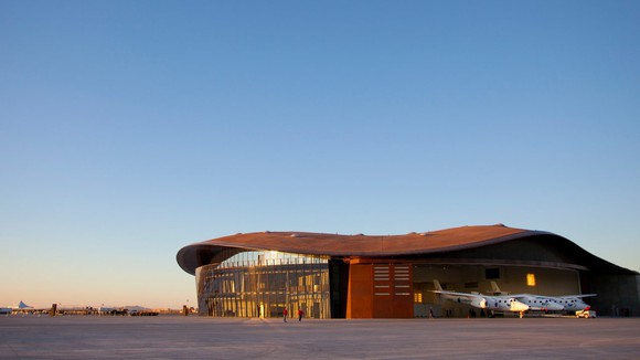 Virgin Galactic's Spaceport America building in New Mexico with spaceship pictured in front of it.