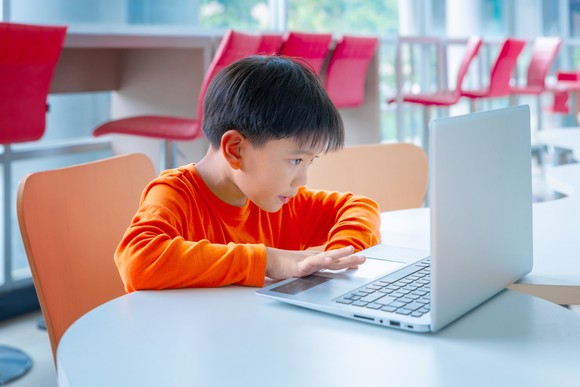 A Chinese boy sitting in front of a laptop computer
