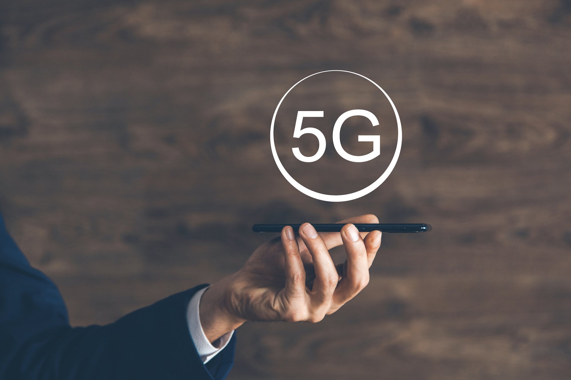Person holding a smartphone with the word 5G above it.