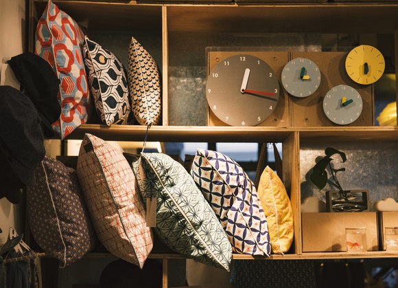 A shelf at a home goods retail store showing pillows and clocks.