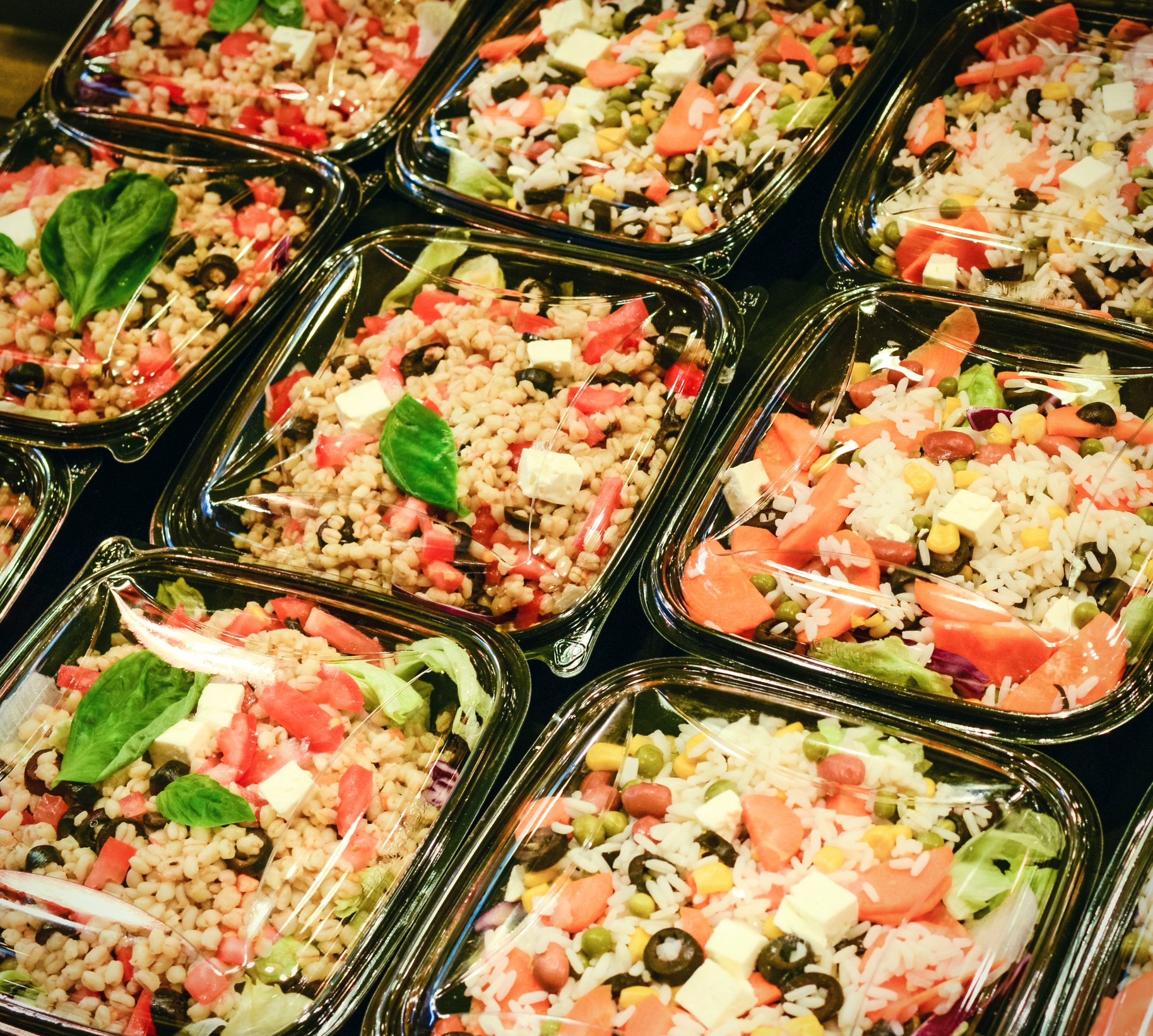 Photograph of pre-packaged meal salads in grocery store cooler.