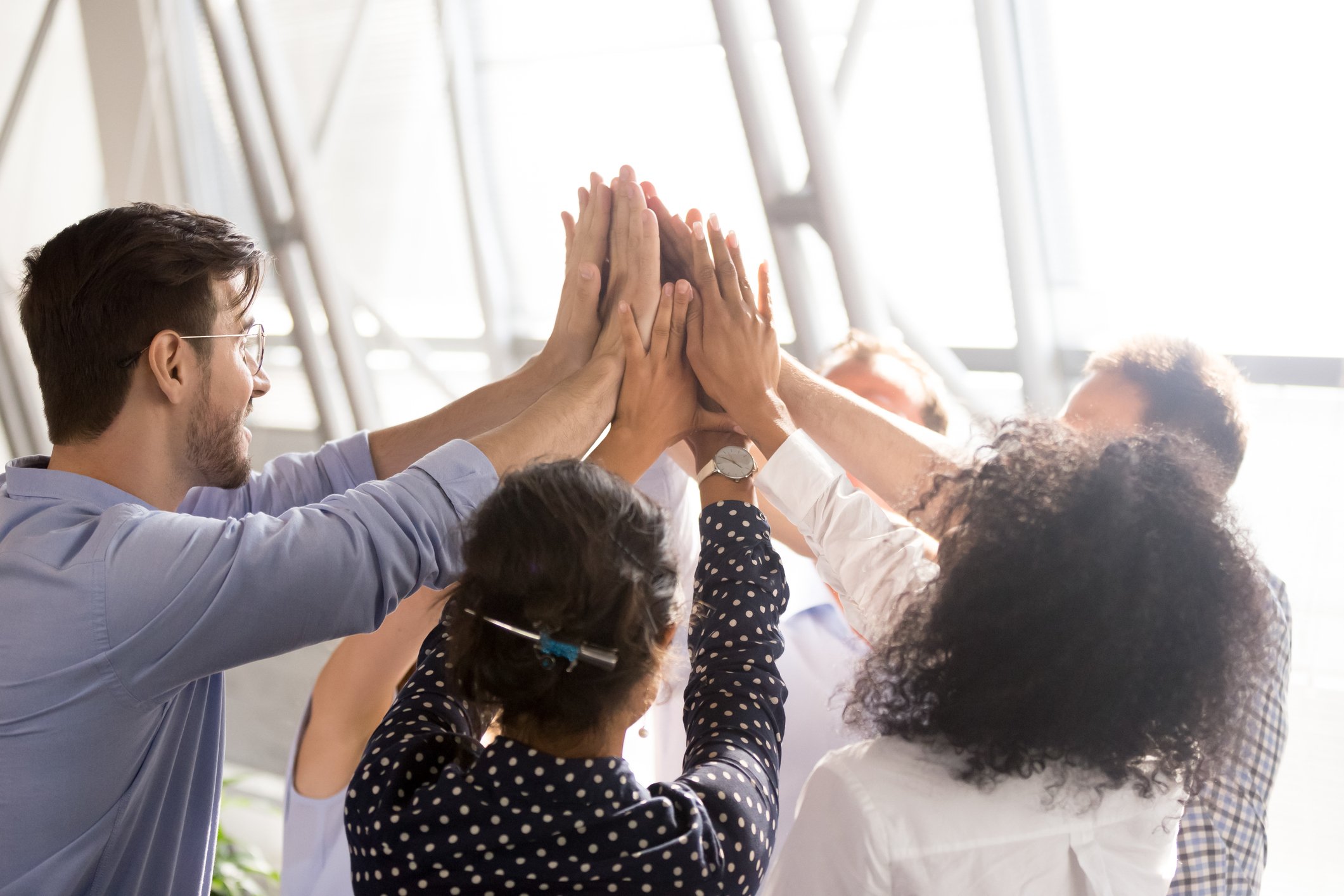 Several office workers giving a joint high five