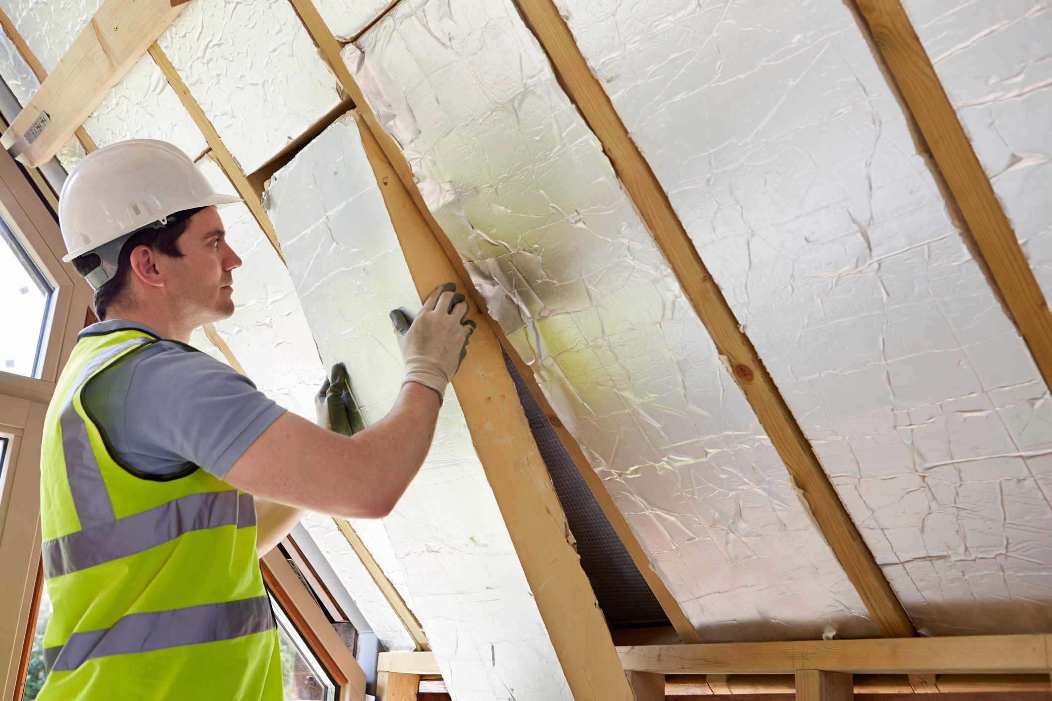 A builder fits insulation into a customer's roof.