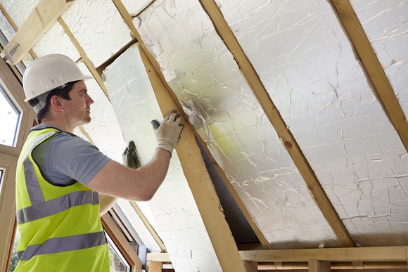 A builder fits insulation into a customer's roof.