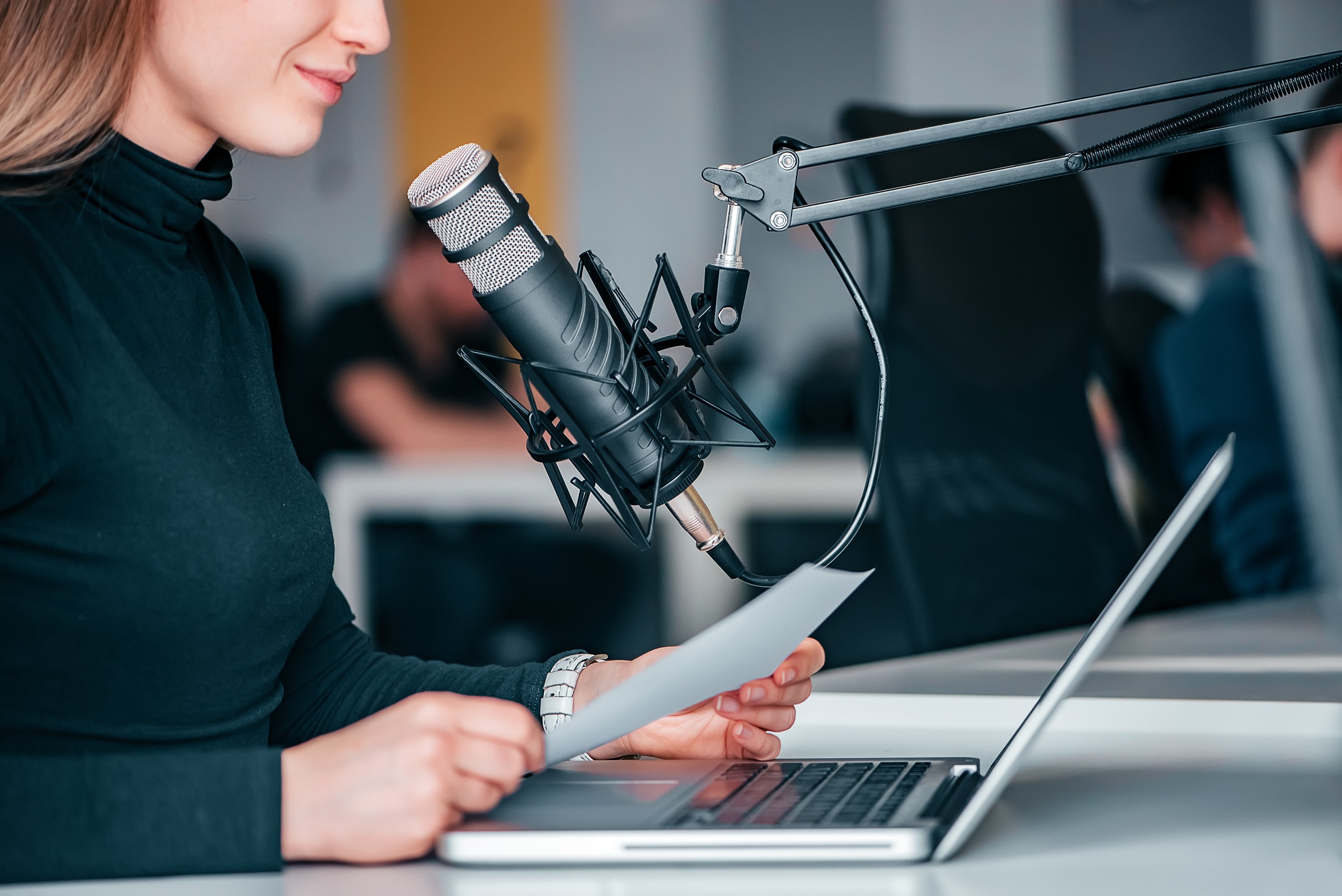 Woman reading into a microphone while creating a podcast