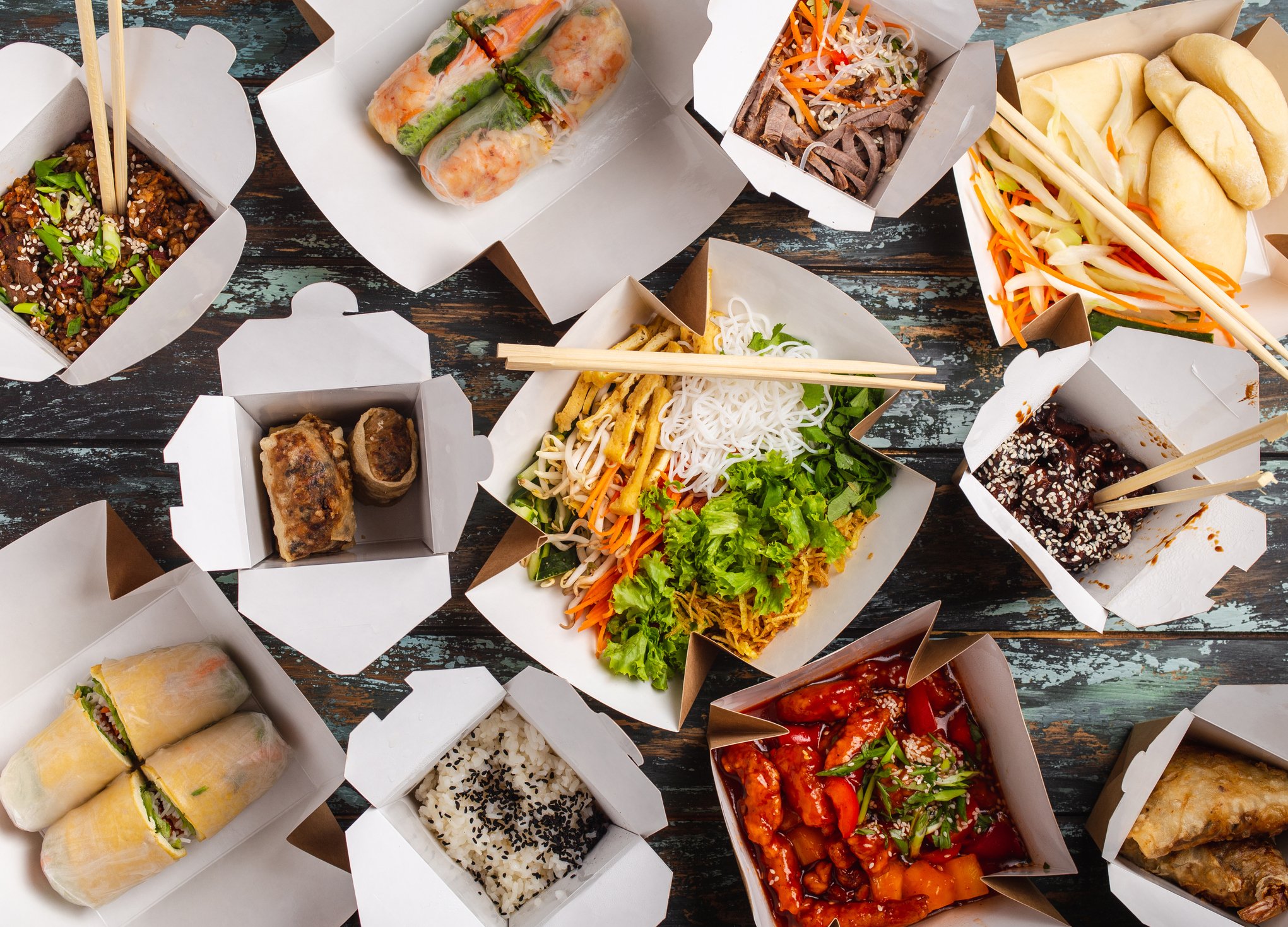 Various types of Asian food in 11 takeout boxes