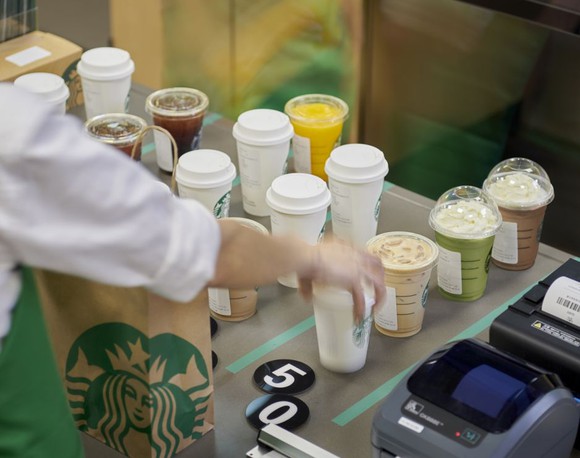Several Starbucks cups stacked awaiting pick-up.
