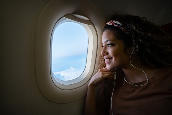 A woman gazes out the window of an airplane.