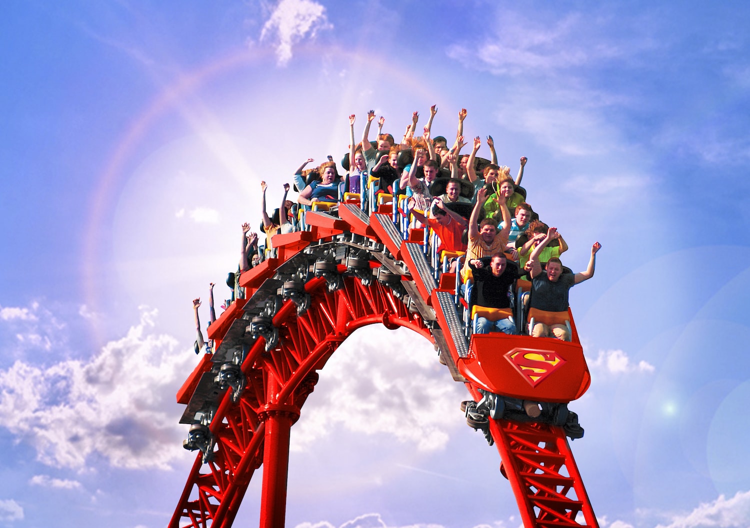 Riders on the Superman coaster at Six Flags going over a hill.