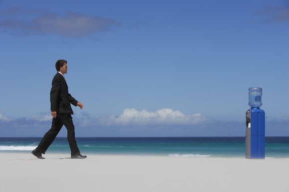 A man on a beach walks toward a water dispenser