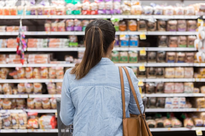 A woman looking at products on grocery store shelves