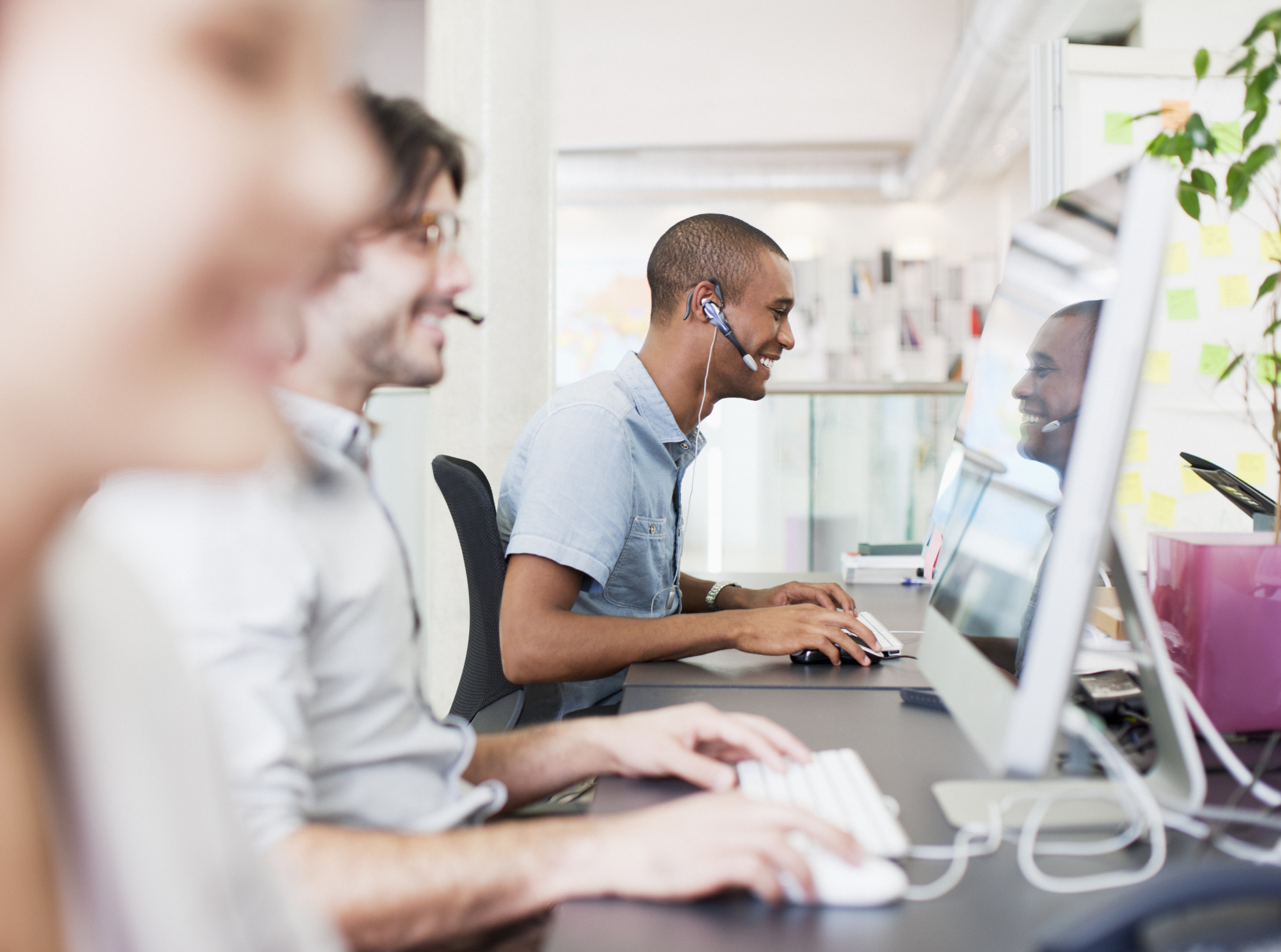 Multiple people wearing headsets in a modern call center.