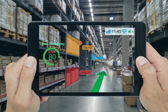 A tablet running an augmented reality app showing virtual graphics being displayed over the camera's view of a warehouse.