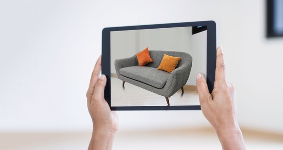 A tablet computer screen showing what a sofa looks like in an empty room using the power of augmented reality.