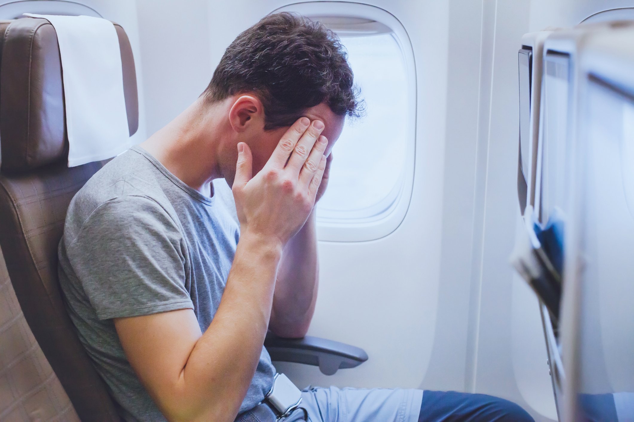 A man suffering a headache aboard an airplane.