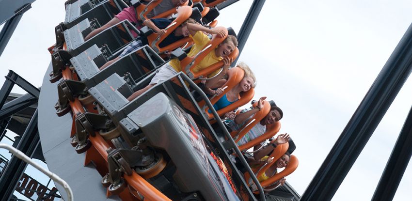 People sitting in a roller coaster car at a Six Flags theme park.