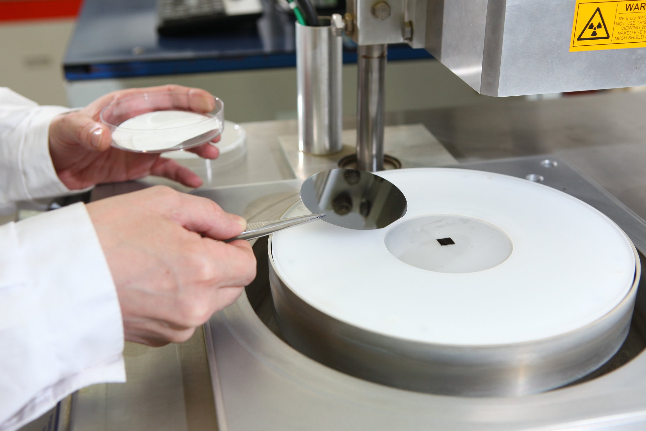 A technician loads an uncut silicon wafer into a machine for analysis and/or processing.