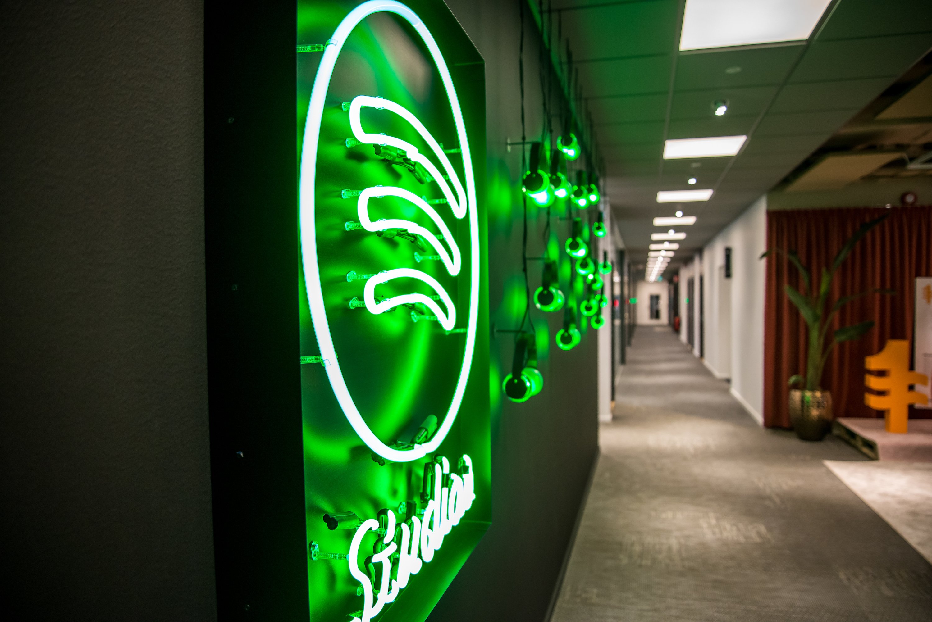 Interior shot of Spotify headquarters showing neon logo hanging on a wall