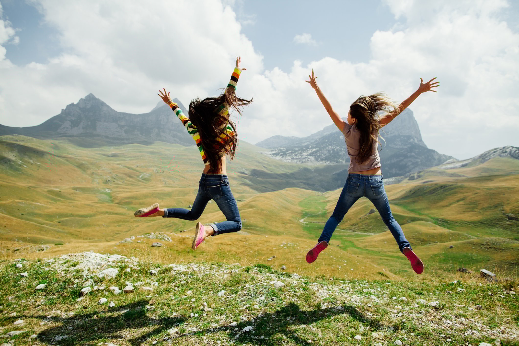 2 women jumping triumphantly in a field.