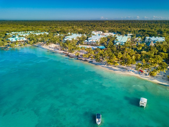 Overhead view of resort surrounded by palm trees and ocean.