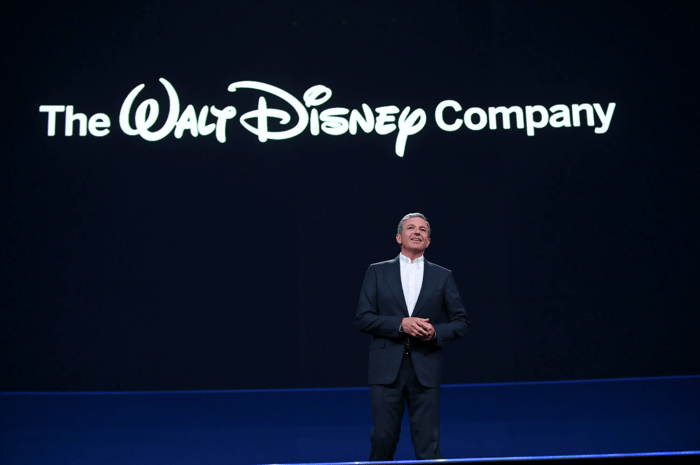 Bob Iger on stage at the Disney investor day with The Walt Disney Company logo projected on a screen behind him.