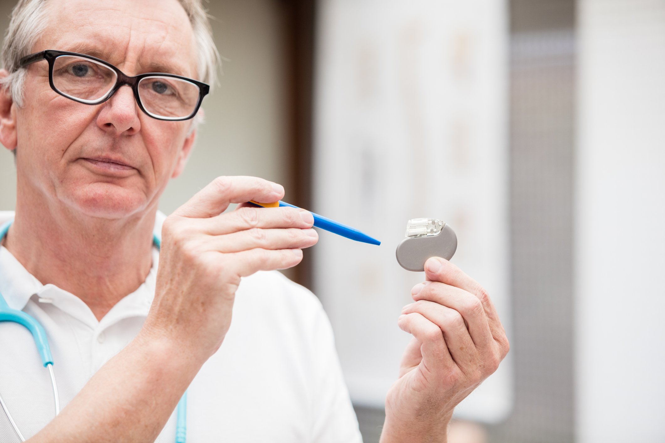 A medical doctor holding a traditional pacemaker in his hand.
