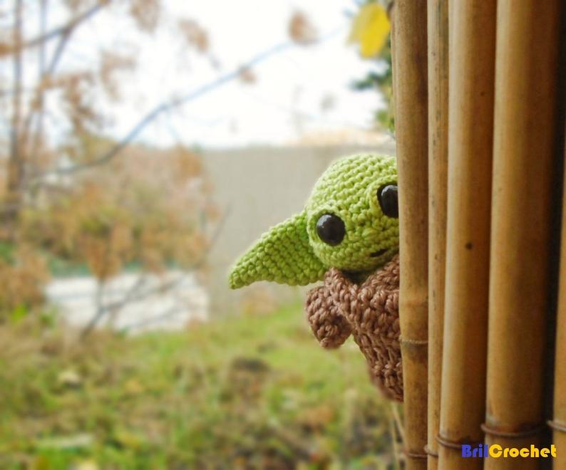 Baby Yoda hiding behind a curtain