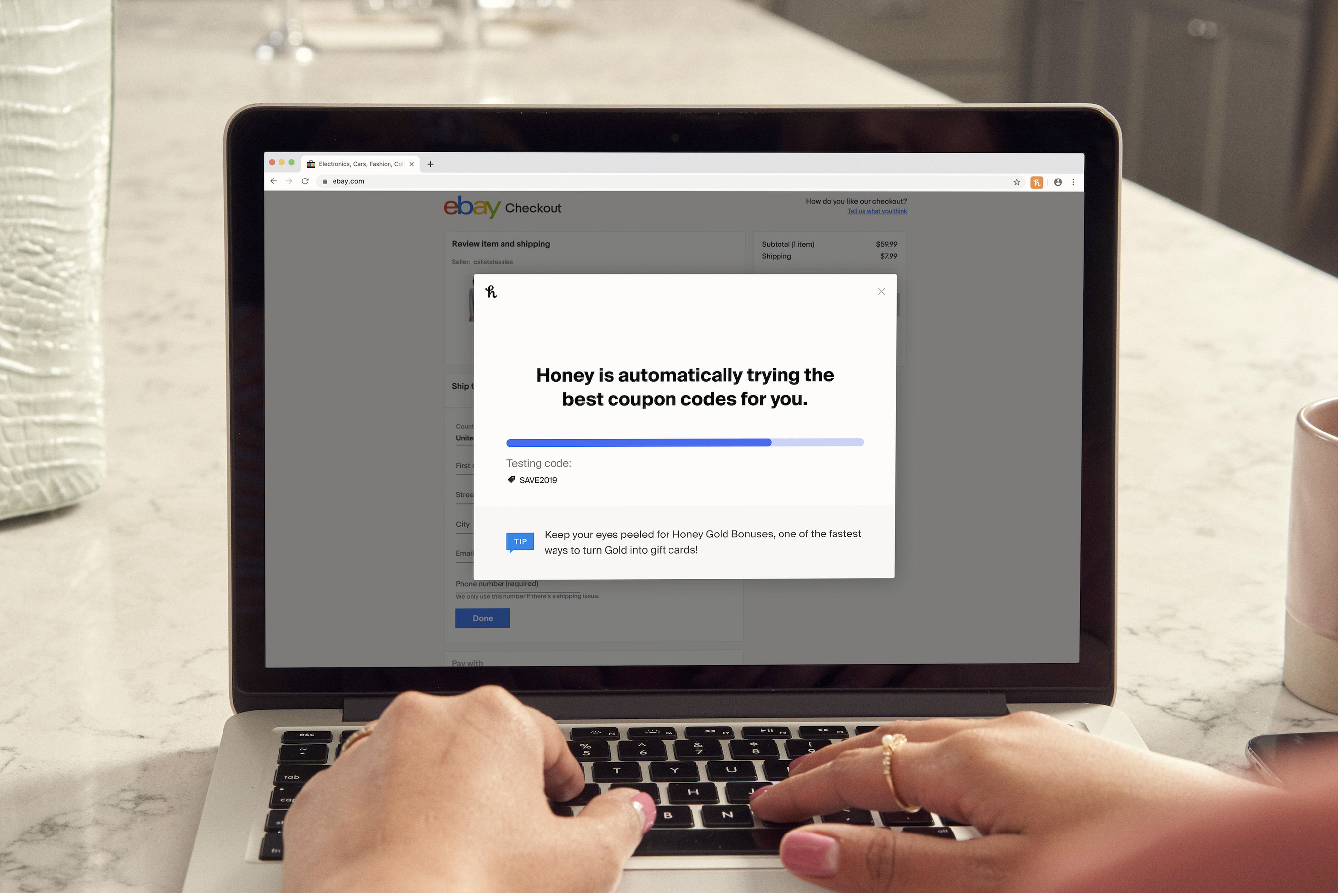 A laptop displaying the Honey browser tool searching for deals while a woman's hands rest on the keyboard.