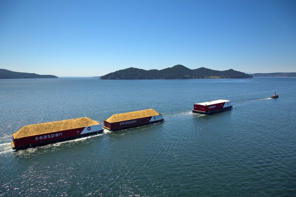 A line of container ships sail past some islands.