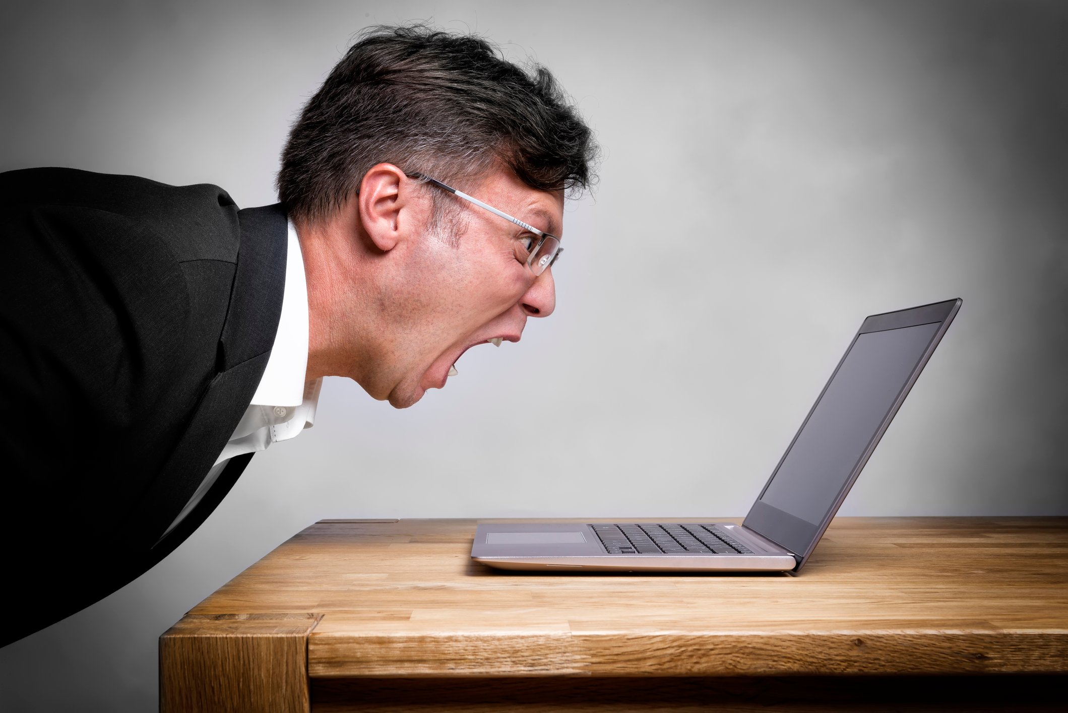 Man screaming at a laptop on a table