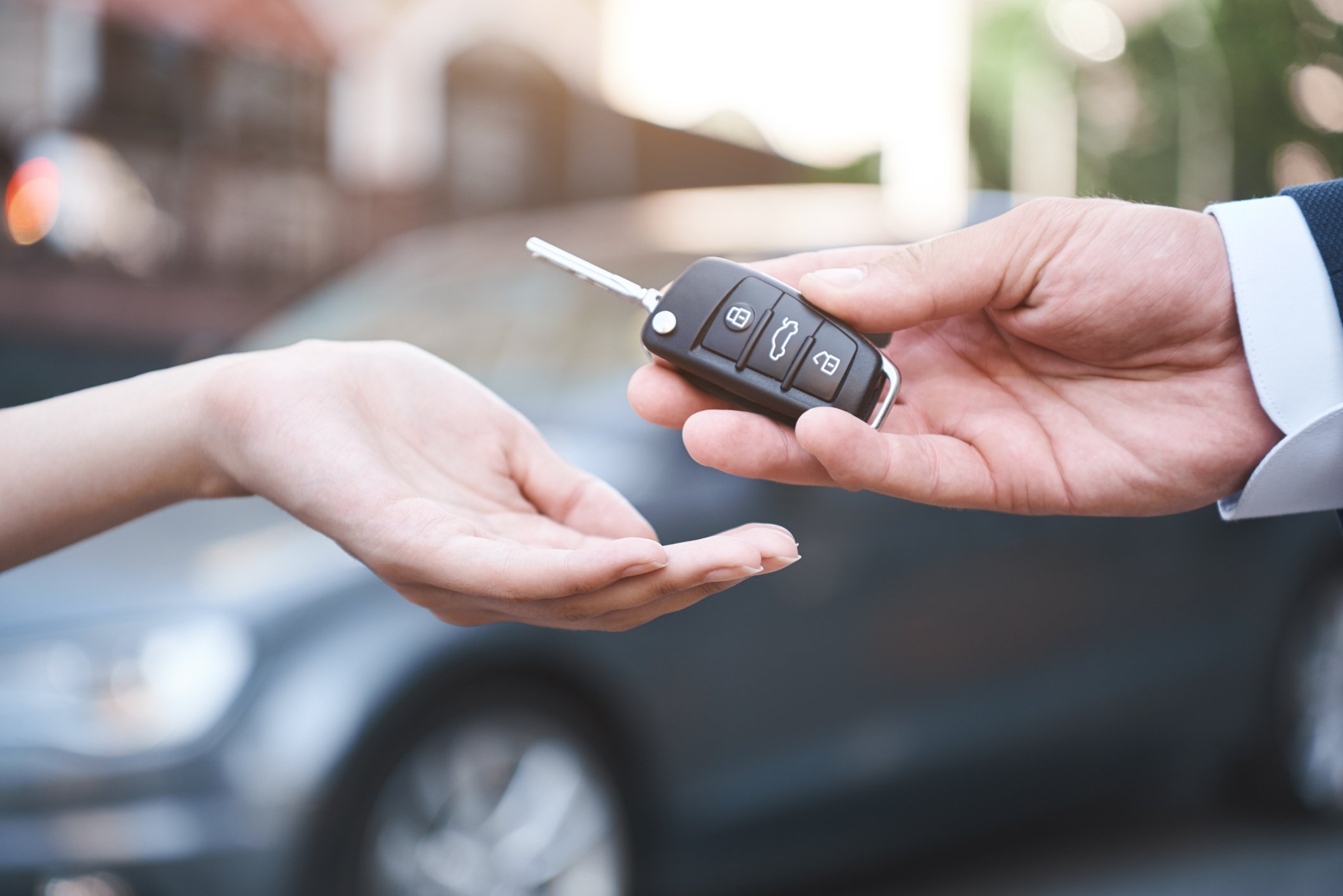 Close-up of a car salesman handing the keys to a car to a customer.