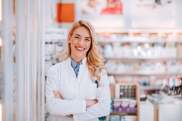 Female pharmacist standing in a pharmacy and smiling.