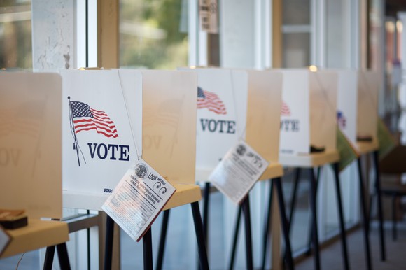 Partitioned voting booths with attached pamphlets. 