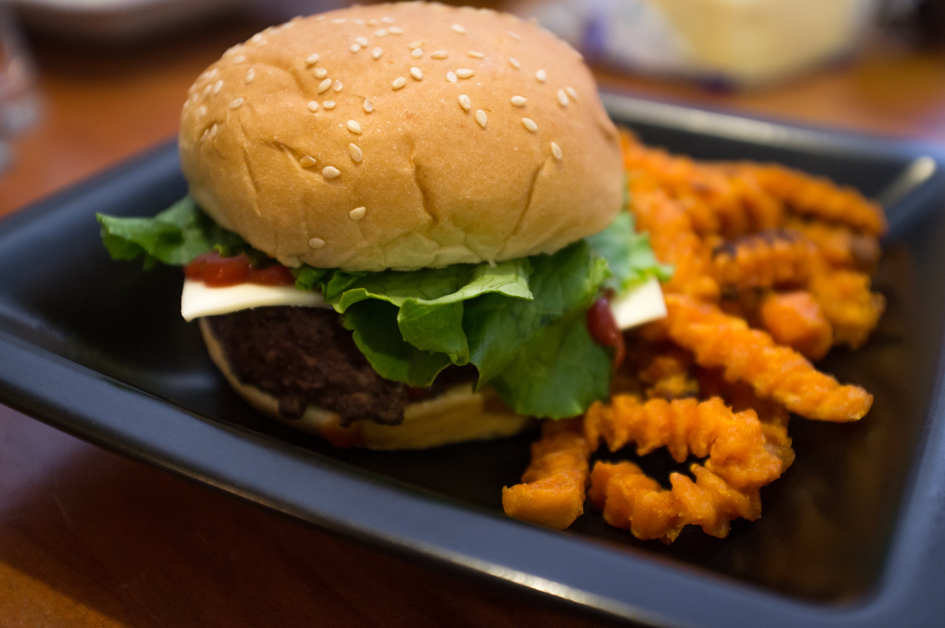 A cheeseburger with lettuce and crinkle fries.
