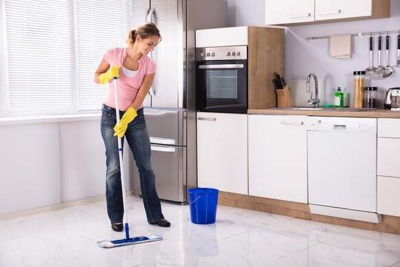 A woman mopping the kitchen floor.