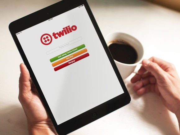 Twilio running on a tablet that's being held by someone holding a cup of coffee.