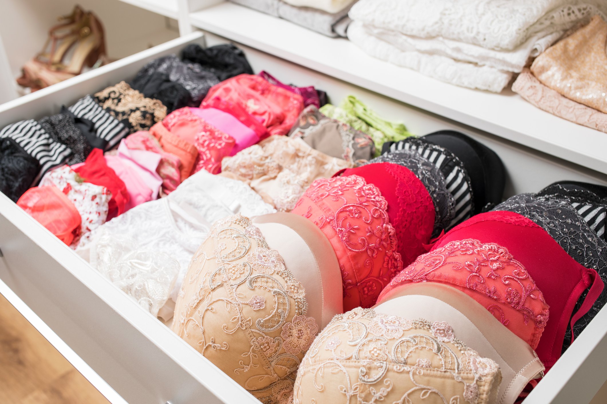 Bras in beige, red, and black are shown in a shop drawer. 