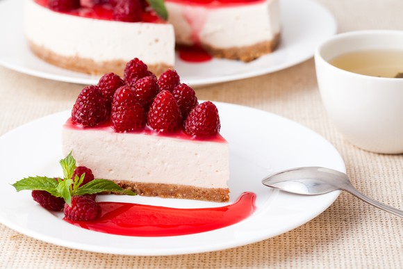 A slice of cheesecake topped with raspberries.