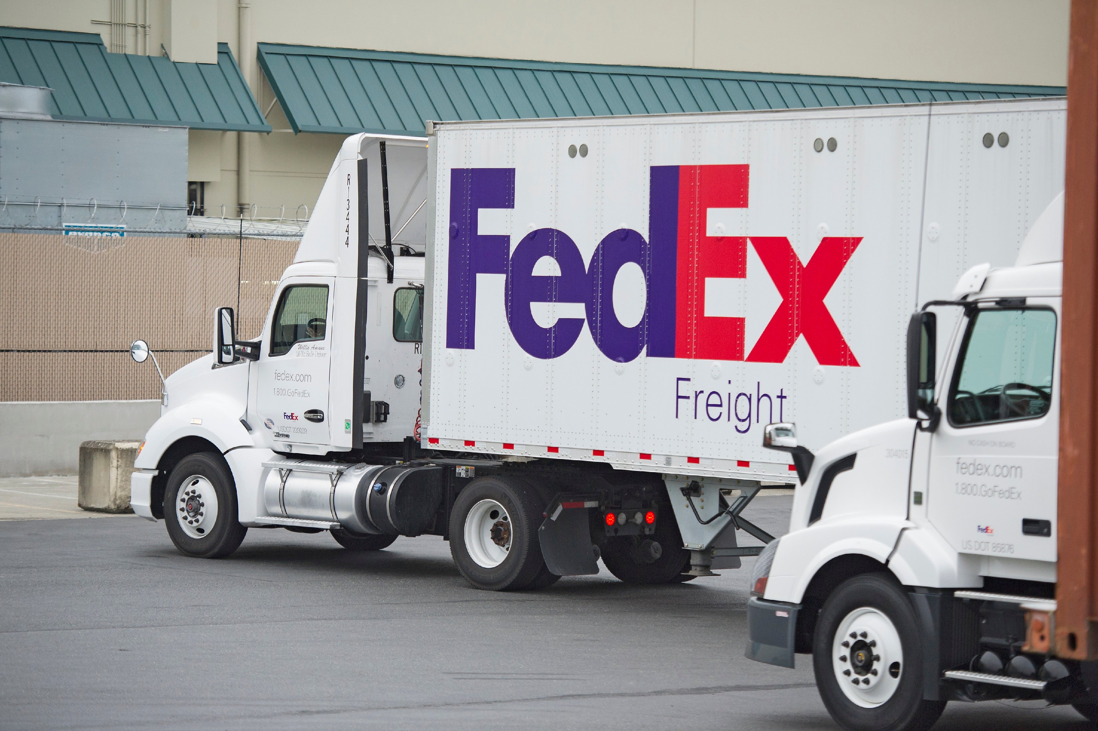 Two FedEx trucks outside of a distribution center.