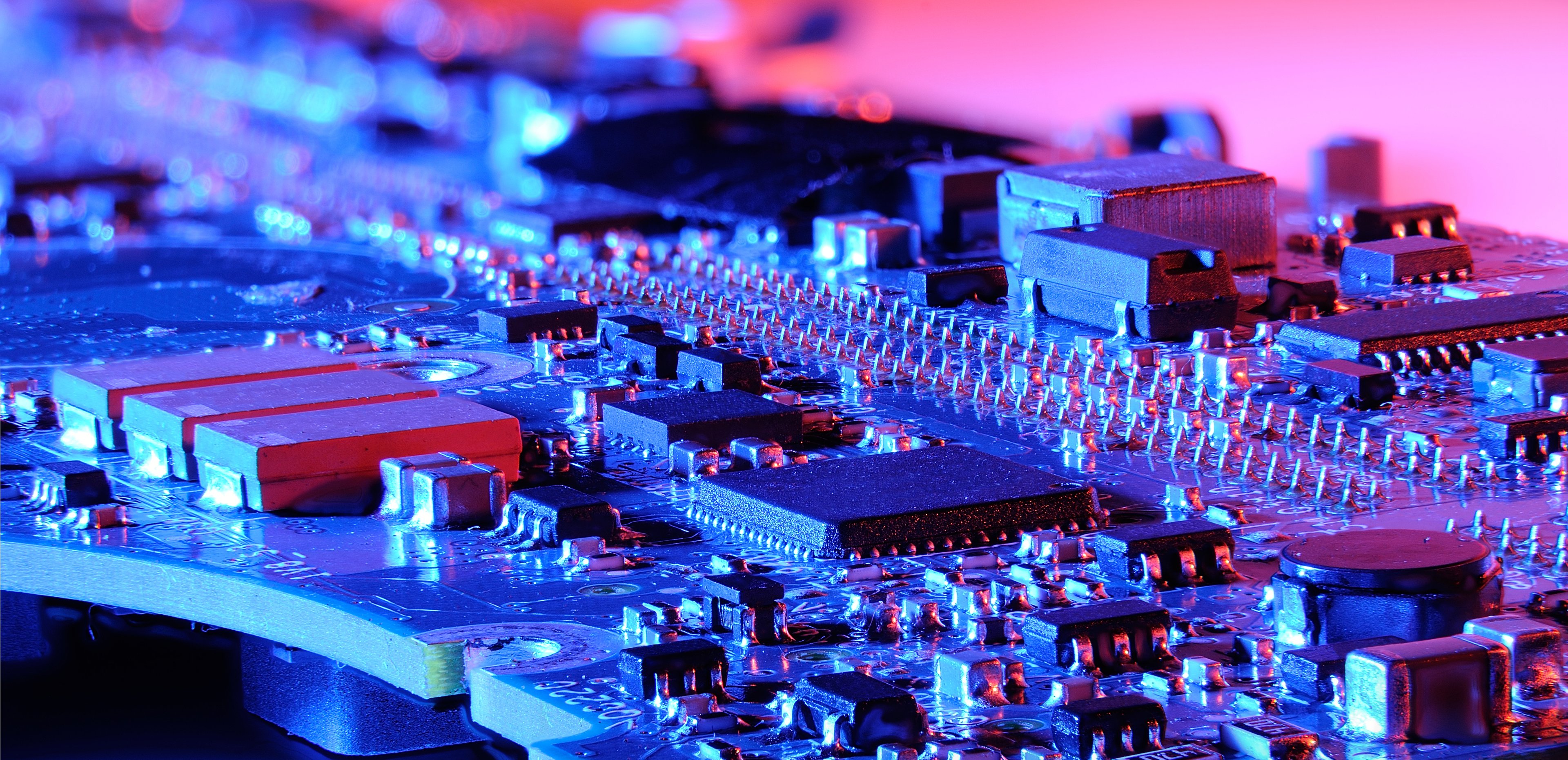 Close-up shot of a fully populated circuit board in red and purple lighting.