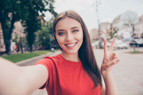 A young woman takes a selfie on a street.