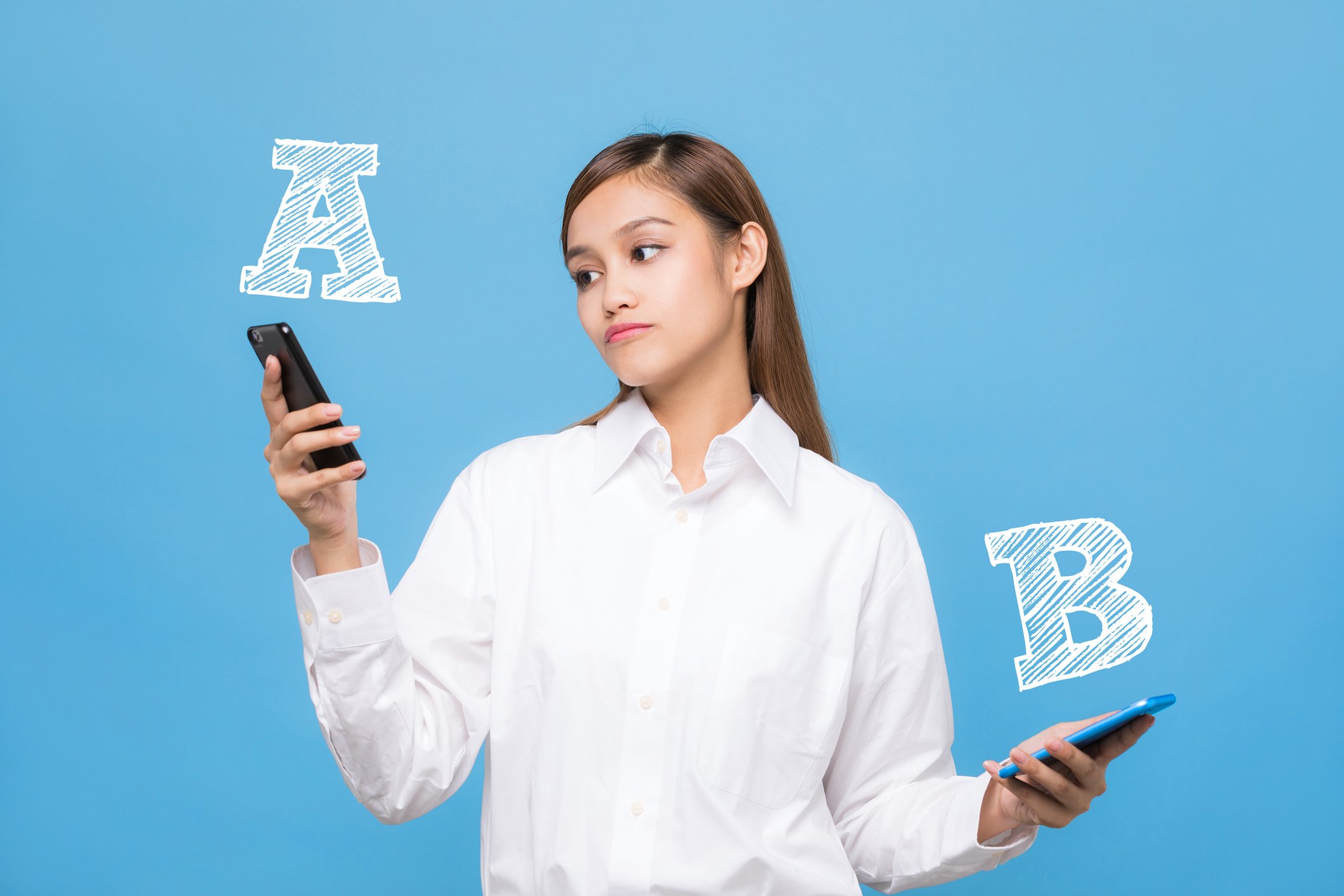 A woman holds a smartphone in each hand. The letter A is above one; the letter B is above the other. She's looking at phone A.