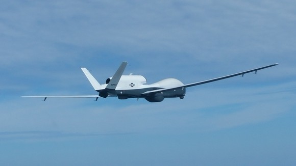 The Triton drone flies over blue skies.