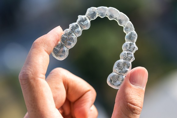Hand holding a clear dental aligner