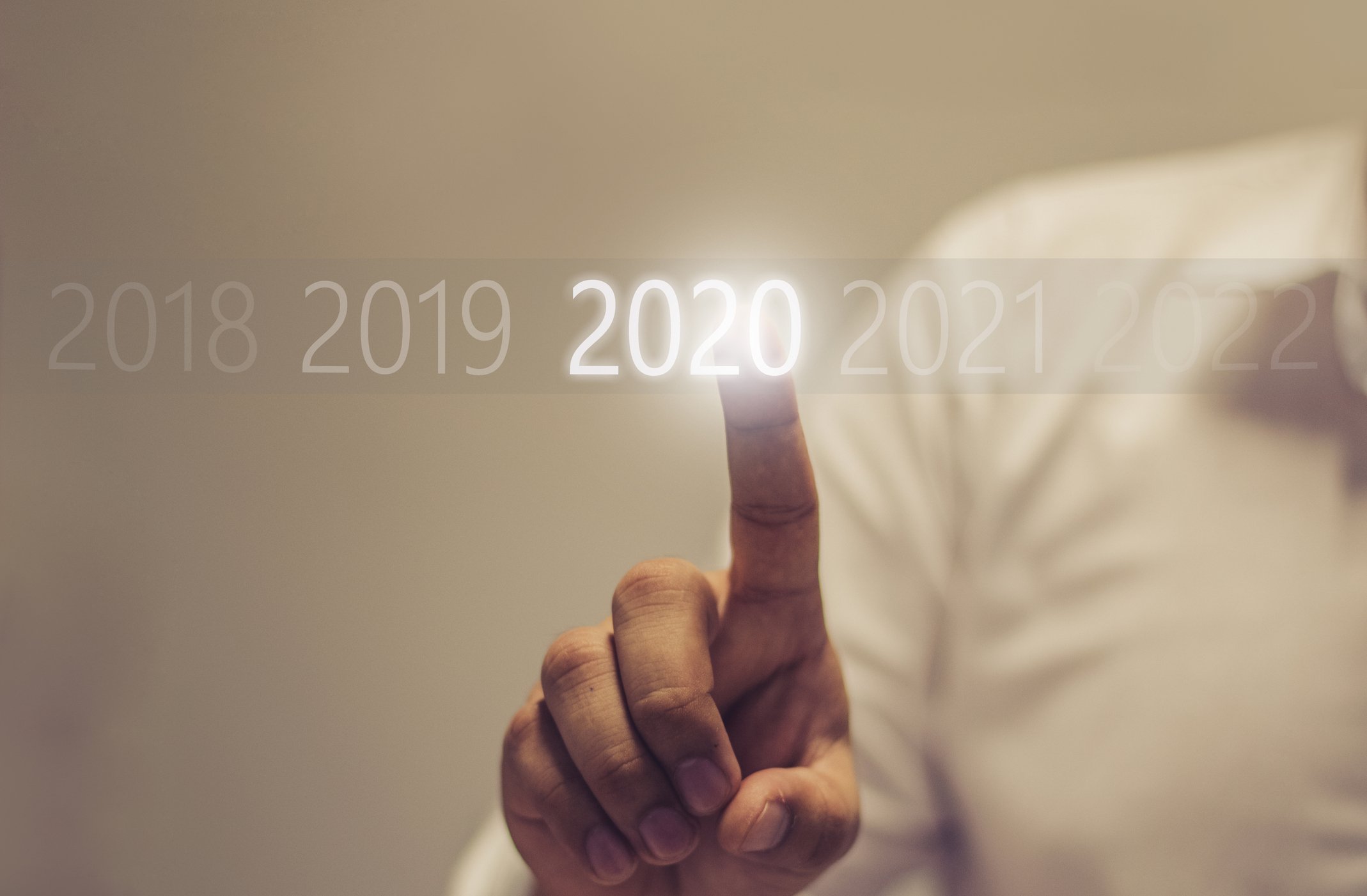 A person touching a lit-up "2020" display.